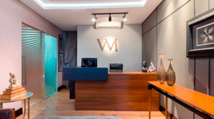 Recepção elegante do escritório Vargas Mildemberg Advogados Associados com balcão de madeira logo VM iluminado e decoração sofisticada representando advogado plano de saúde empresarial quando contratar