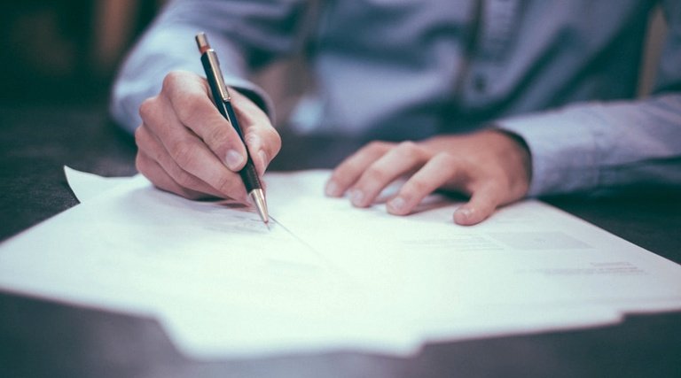 Profissional assinando documentos de transação imobiliária antes do pagamento do sinal