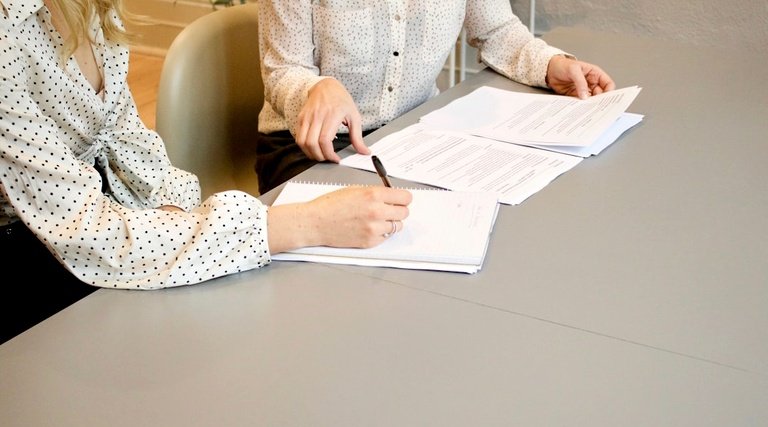 Advogado revisa contrato de compra e venda de imóvel com cliente em mesa de escritório