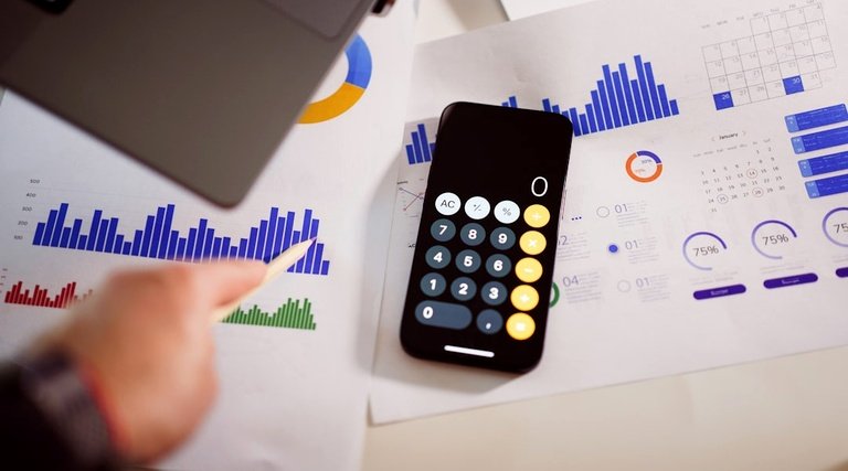 Pessoa calcula rubricas indenizatórias sobre gráficos financeiros e relatórios de atraso na entrega de imóvel