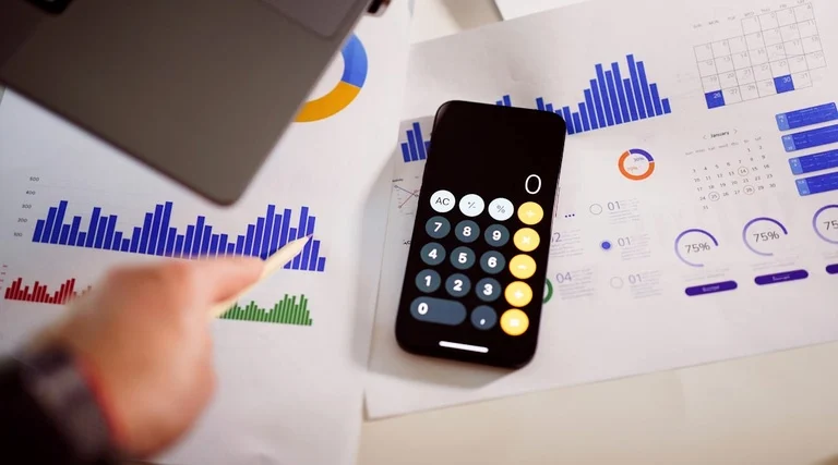 Pessoa calcula rubricas indenizatórias sobre gráficos financeiros e relatórios de atraso na entrega de imóvel