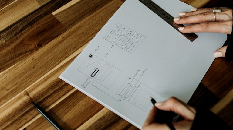 Mãos analisam plantas técnicas de obra sobre mesa, contexto de fiscalização de prazos contratuais de entrega