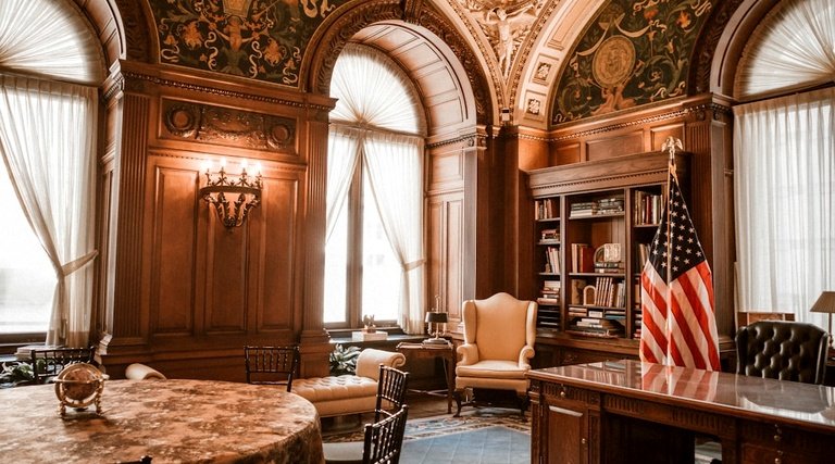 Escritório de advocacia clássico com estante de livros jurídicos, mesa executiva e bandeira americana