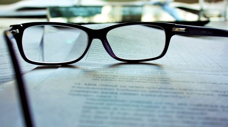Óculos sobre contrato impresso durante revisão técnica detalhada de cláusulas imobiliárias