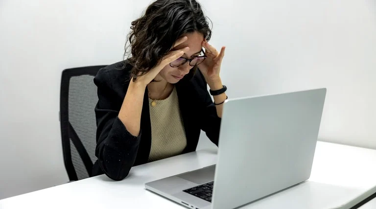 Profissional preocupada diante do notebook após negativa de financiamento imobiliário