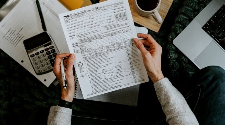 Pessoa analisa formulário de IPTU e calculadora sobre mesa, representando autuações fiscais em imóvel sem habite-se