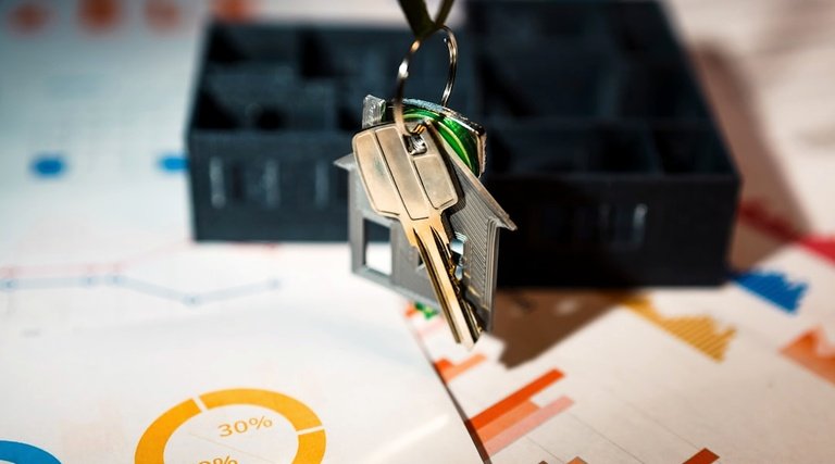 Chaveiro com pingente de casa sobre documentos e miniatura de imóvel ao buscar advogado imobiliário especializado