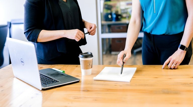 Advogado Imóvel Luxo Análise Documentos Advogado para imóvel de luxo: duas pessoas analisando documentos sobre mesa de madeira com notebook e café