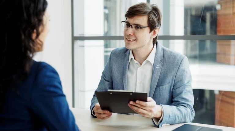 Advogado em Santa Catarina: profissional de blazer segurando tablet durante conversa com cliente em ambiente corporativo