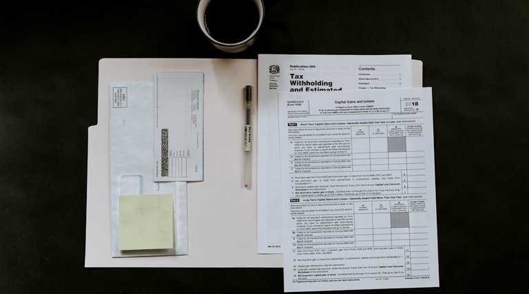 Advogado imóvel luxo documentação fiscal Advogado para imóvel de luxo: formulários fiscais, envelopes e caneta organizados sobre mesa de trabalho