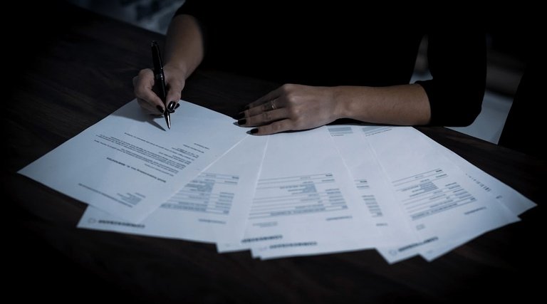 processar xp investimentos: Profissional analisa documentos financeiros e contratos de investimento sobre mesa