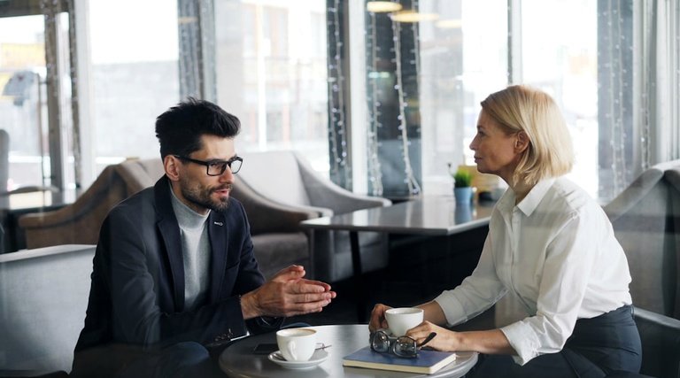 Advogado em Santa Catarina: profissional de blazer e óculos conversando com cliente em ambiente corporativo