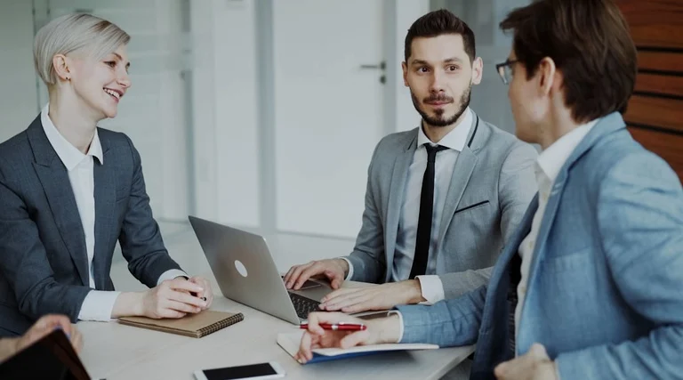 Advogado Holding Familiar em Reunião Profissional Advogado holding familiar em reunião com dois clientes em mesa de trabalho com laptop e documentos