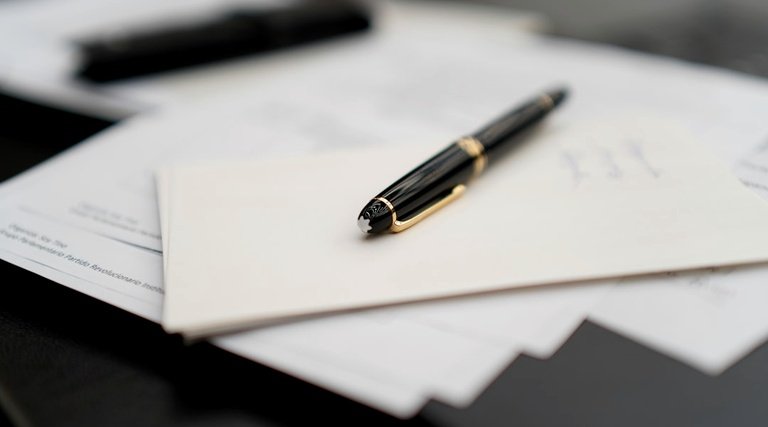 imóvel quitado e não entregue: Caneta sobre documentos contratuais relacionados à quitação e entrega de imóvel
