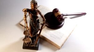 Estátua da Justiça com balança ao lado de martelo e livro jurídico representando processos de imposto de herança