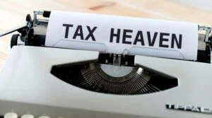 holding patrimonial vantagens e desvantagens: Máquina de escrever exibe texto TAX HEAVEN representando estratégias