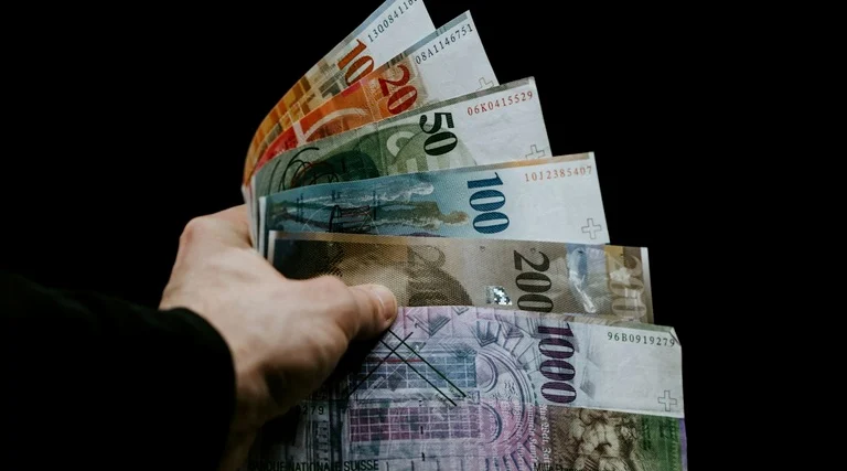holding patrimonial vantagens e desvantagens: Mão segura leque de cédulas de real em diferentes valores para ilustrar